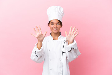 Little caucasian chef girl isolated on pink background counting ten with fingers