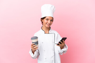 Little caucasian chef girl isolated on pink background holding coffee to take away and a mobile