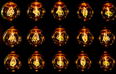 Isolated group of 15 yellow gold luminous retro classical spherical light bulbs in 3 rows with...