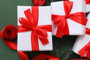 Christmas gifts tied with red ribbon on green background, closeup