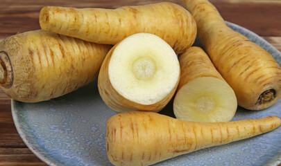 Closeup of group many raw isolated sliced parsnip root vegetables on blue china plate