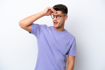 Young caucasian man isolated on white background doing surprise gesture while looking to the side