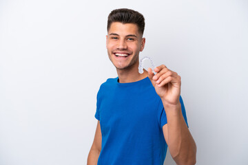 Young caucasian man holding invisible braces isolated on white background with happy expression