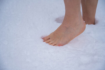 Close-up of a woman walking barefoot in the snow. Boosting immunity with cryotherapy.