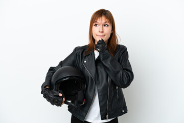 Redhead girl with a motorcycle helmet isolated on white background having doubts and thinking