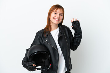 Redhead girl with a motorcycle helmet isolated on white background saluting with hand with happy expression