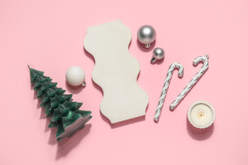 Christmas tree candle with podium, candy canes and balls on pink background