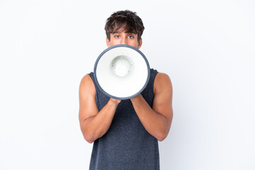 Young sport caucasian man isolated on white background shouting through a megaphone