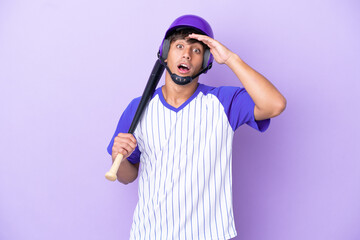 Baseball caucasian man player with helmet and bat isolated on blue background doing surprise gesture while looking to the side