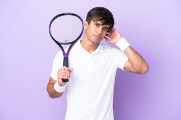 Handsome young tennis player man isolated on ocher background having doubts