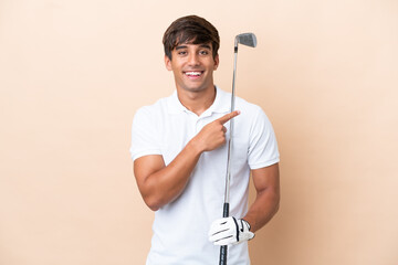 Young golfer player man isolated on ocher background pointing to the side to present a product