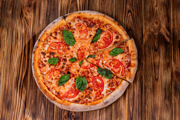 Delicious fragrant pizza-Margherita with mozzarella, tomatoes and basil on tomato sauce on woden background. Copy space
