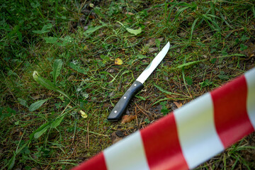 Kitchen knife at the crime scene fenced with red tape. The crime scene is on the street. Criminal...