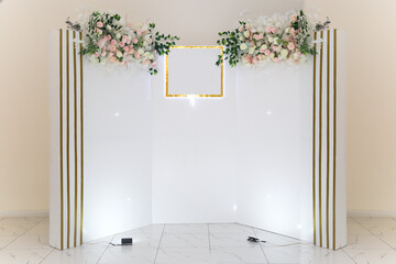 White photo zone with delicate flowers for the hero of the day in the cafe.