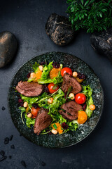 Portion salad beef steaks, lettuce, arugula, tomatoes, tangerines and hazelnuts.