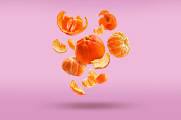 Fresh tangerines are falling in the air, isolated on a pink background. Food levitation,...