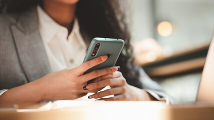 Close up american woman holding smartphone, she is using smartphone browsing social media and chatting with friends on online messaging app. The concept of using a smartphone.