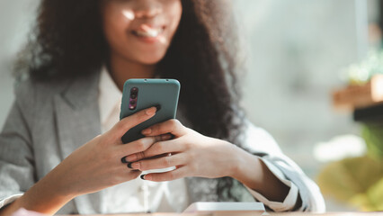 Close up american woman holding smartphone, she is using smartphone browsing social media and chatting with friends on online messaging app. The concept of using a smartphone.