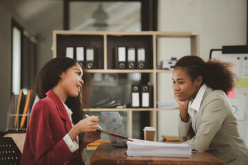 Two American women are working together in the office of a startup company. They are having a brainstorming and planning meeting in a joint department, women leading the way. Concept of women's work.