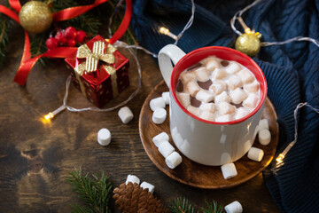 Christmas drink concept. Christmas winter cozy cup hot chocolate drink with marshmallow and christmas lights, sweater knitted on a rustic background. Copy space.