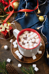Christmas drink concept. Christmas winter cozy cup hot chocolate drink with marshmallow and christmas lights, sweater knitted on a rustic background.