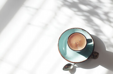 Ceramic cup with coffee on a background with shadows