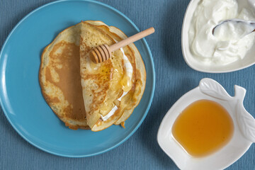Mofletta (Moroccan Jewish crepe) with honey and cream cheese on blue background.