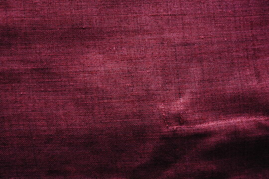 Fabric texture background. Burgundy purple fabric with weave. Natural slightly wrinkled look of the material. Uniform copy space background. Cotton, canvas or woolen thin fabric laid on the surface.