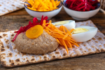 Fototapeta na wymiar Gefilte fish for Jewish holiday Pesach (Passover) over matzah with carrot salad and eggs.