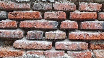 Abstract background of old vintage broken red brick wall of an old house in the urban area during daylight