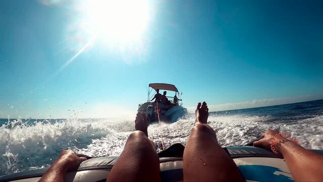 water skiing over inflatable donut pulled by motorboat. Aquatic sports, water sport during summertime, ski water donuts.