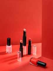 Composition with makeup products. Lipstick and nail polish. Cosmetic products advertisement on red background with Hard light. Product Advertising environment. Sale of beauty products concept.