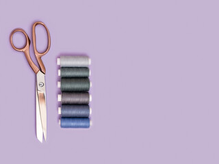 Minimalist scene of tailoring accessories. Flat lay with pink gold scissors and bobbins. Handmade, DIY, crafts, art or sewing concept. Clothes design and dressmaking. Copy space.
