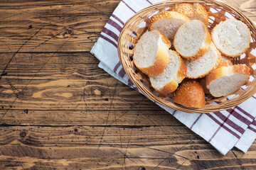 Fresh white bread, baguette slices in a wicker basket. Wooden rustic table background. Copy space