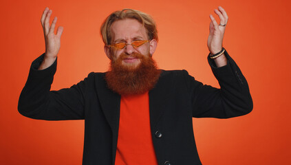 Excited amazed man 20s in jacket touching head and showing explosion, looking worried and shocked, professional burnout. Looking surprised wow guy isolated alone on orange studio wall background