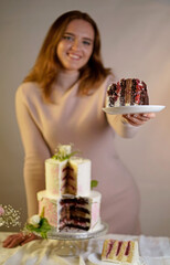 Girl cuts and serves a piece of cake. festive wedding two-tiered cake decorated with fresh flowers on a gray background