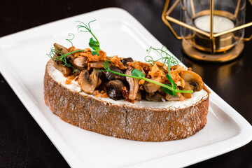 Italian food bruschetta with porcini mushrooms, cream cheese and green peas, closeup.