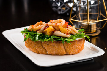 Italian bruschetta with fried squid, arugula, cream cheese and sauce.