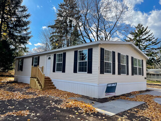 Brand new prefab mobile home with for sale yard sign post, colorful fall foliage near Rochester,...