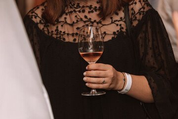 Glass of rose wine held by a person at a premium wine tasting with friends and loved ones.