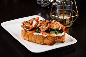 Bruschetta with fried chicken pieces, tomatoes, peppers, arugula, cream cheese and sauce.
