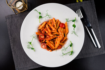 Italian food pasta Penne with tomatoes in tomato sauce garnished with green peas.