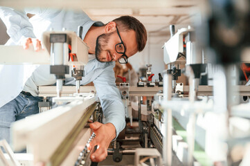 Process of using the cutting machine. Print house worker in white clothes is indoors