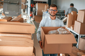 Moving the boxes with raw material. Print house worker in white clothes is indoors