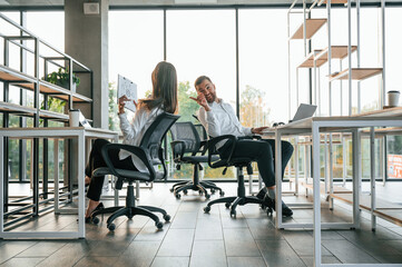 Talking to each other. Man and woman are working in the modern office together