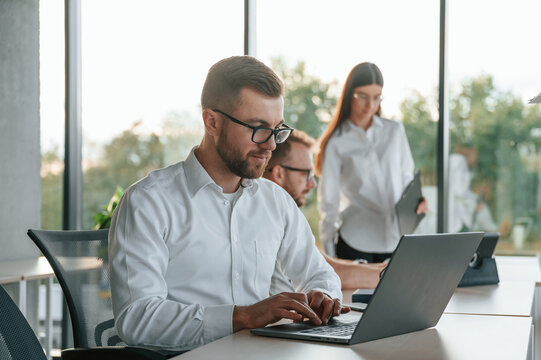 Sitting By Laptop. Three People In Formal Clothes Are Working In The Modern Office Together