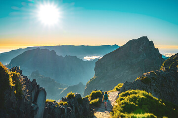 Sporty woman with backpack walking along super scenic hike trail on Pico do Ariero in the evening...