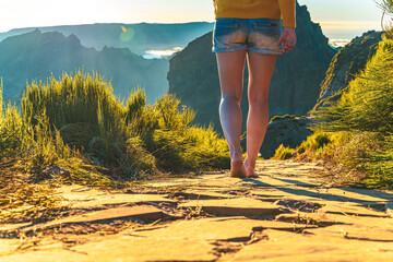 Legs of an athletic woman walking barefoot in the evening sun on Pico do Ariero on a super...