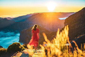Beautiful woman in red dress walking barefoot on a very scenic hiking trail in the evening sun on...