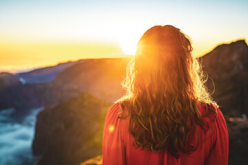 Beautiful woman in red dress enjoying sunny evening atmosphere on Pico do Ariero. Verade do Pico Ruivo, Madeira Island, Portugal, Europe.